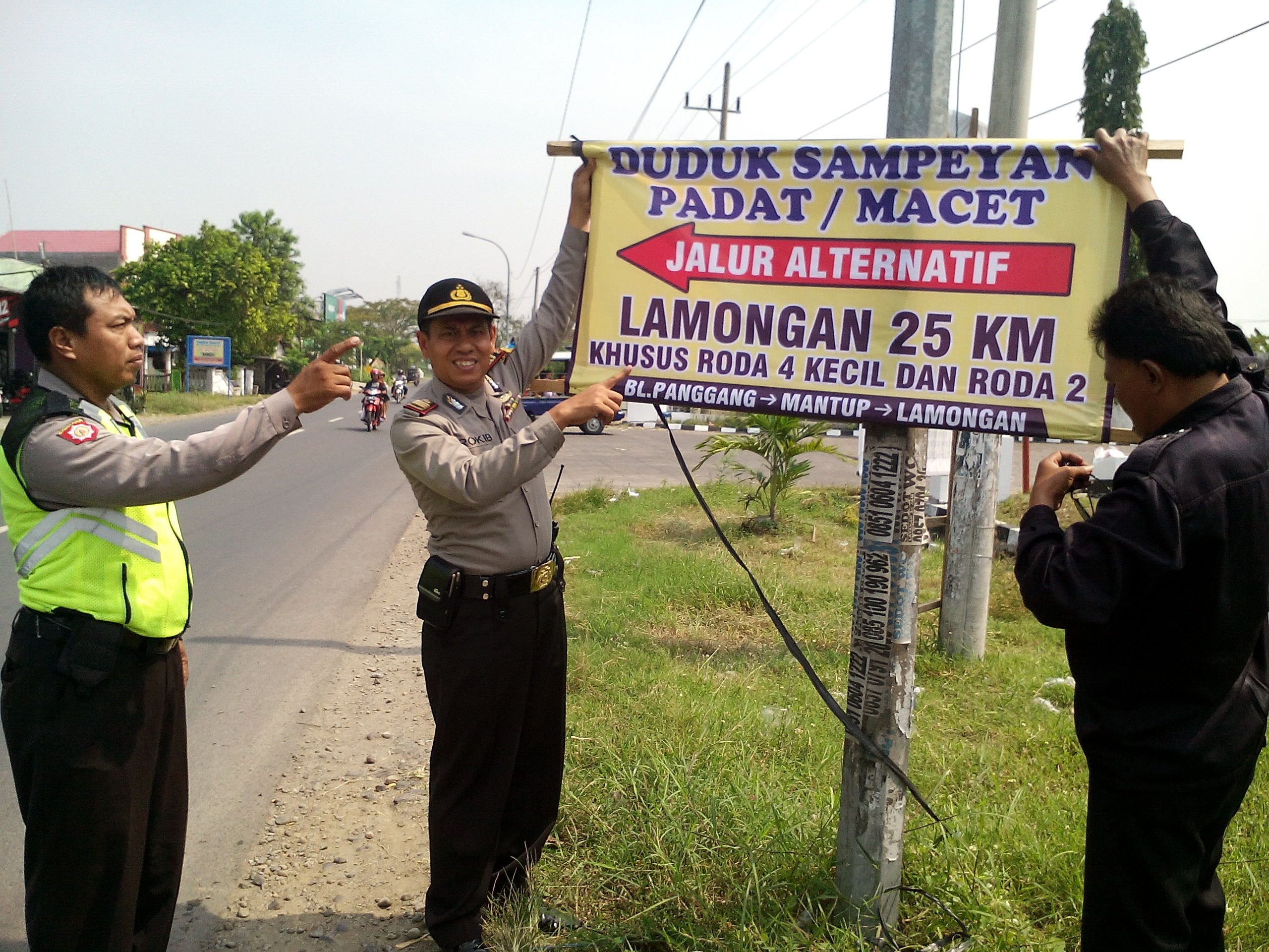 Kapolsek Balongpanggang, AKP Abdul Rokip memasang sepanduk penunjuk arah.