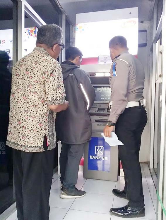 Kanit Tilang, Bripka Suyanto saat memandu pelanggar untuk membayar biaya tilang di ATM