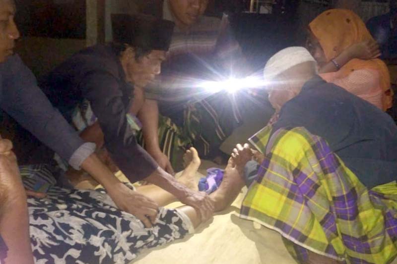 Serma Suwanto membantu memberikan penerangan dengan menggunakan sinar cahaya lampu dari HP yang dimilikinya, sebut saja ibu marinem (54 Th)